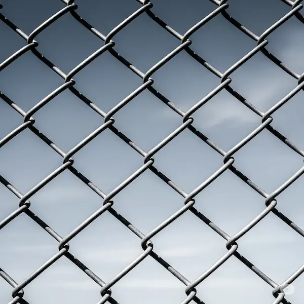 A close-up of a chain link fence against a clear sky.