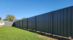 A newly erected dark-grey steel fence in a Buffalo, NY, neighborhood on a sunny day, showcasing its durability.